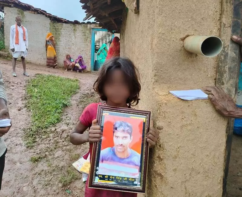 The deceased tribal residents daughter holding her fathers photograph.