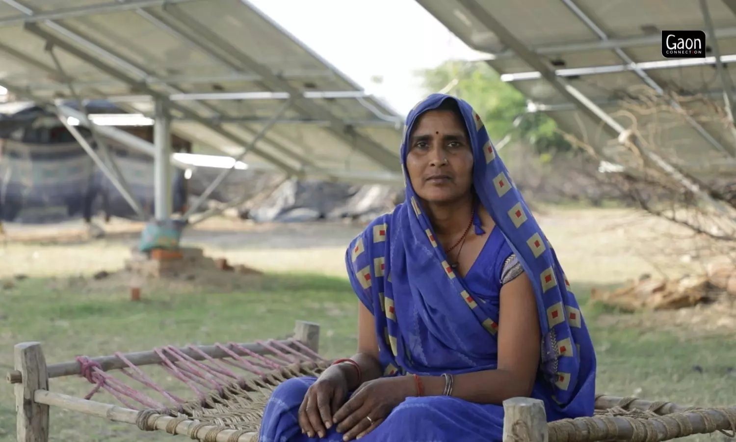 Laxmi Devi sits on a charpoy while her fields get irrigated using a solar pump, in Tindouli village, Mahoba, Uttar Pradesh.