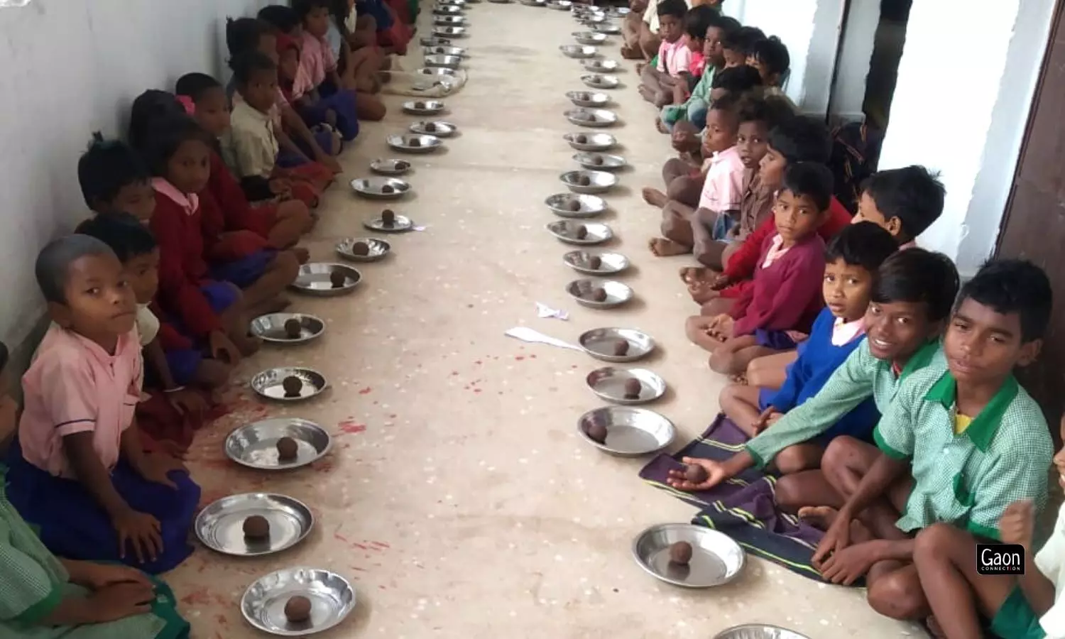 Children having madua laddus in their mid day meal. 